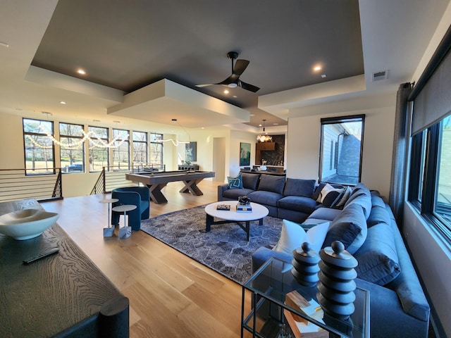 interior space with a wealth of natural light, a raised ceiling, ceiling fan, and wood finished floors