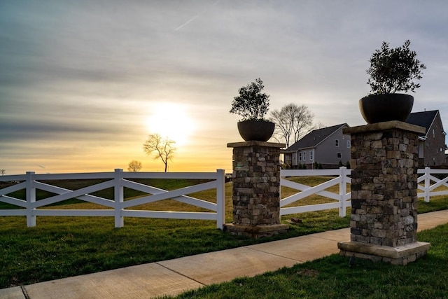 gate at dusk with fence and a yard