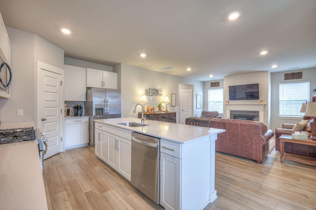 kitchen with a sink, open floor plan, white cabinetry, and stainless steel appliances