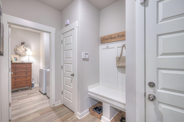 mudroom featuring baseboards, light wood-style flooring, and washing machine and clothes dryer