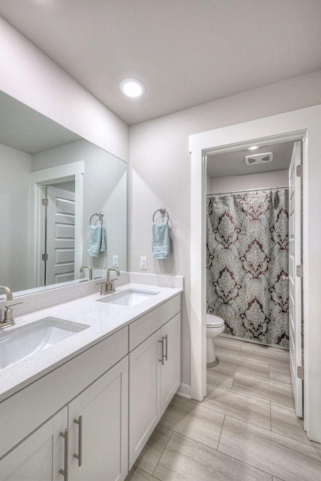 bathroom featuring visible vents, a sink, toilet, and double vanity