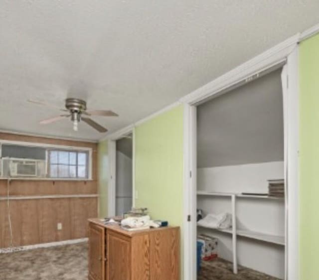 kitchen with wooden walls, brown cabinetry, ceiling fan, cooling unit, and carpet flooring