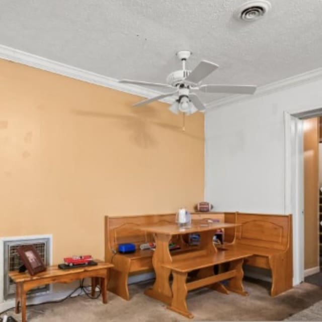 carpeted dining room featuring visible vents, crown molding, a textured ceiling, and ceiling fan