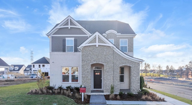 view of front of home featuring stone siding, brick siding, and a front lawn