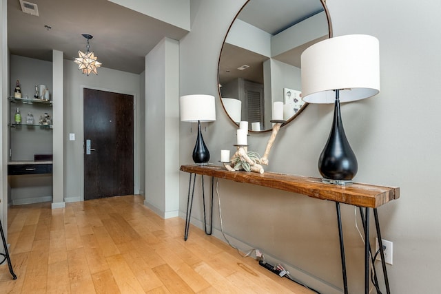 entrance foyer with baseboards, visible vents, and hardwood / wood-style floors