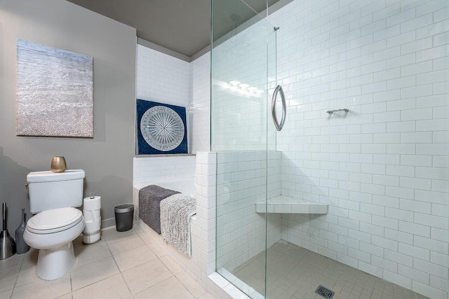 bathroom featuring a stall shower, tile patterned flooring, a garden tub, and toilet