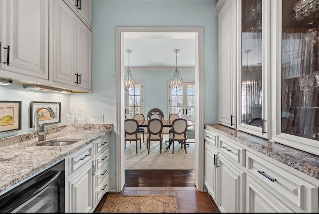 kitchen with light stone counters, beverage cooler, dark wood-type flooring, a sink, and white cabinetry