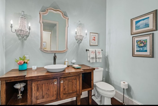 bathroom with baseboards, vanity, toilet, and an inviting chandelier