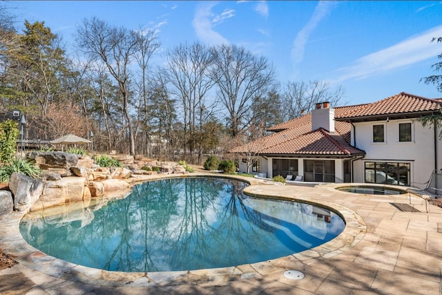 pool featuring an in ground hot tub and a patio area