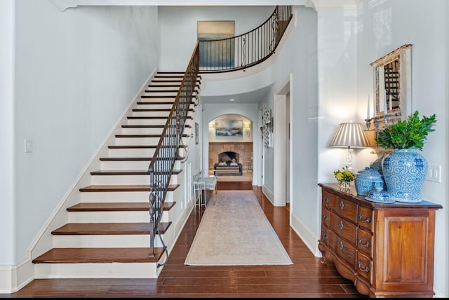 entryway with baseboards, stairway, dark wood-style flooring, a high ceiling, and a fireplace