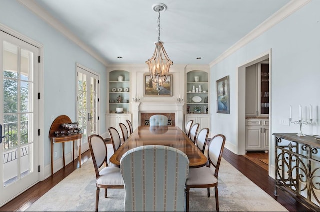 dining space with built in features, dark wood-style flooring, crown molding, and an inviting chandelier