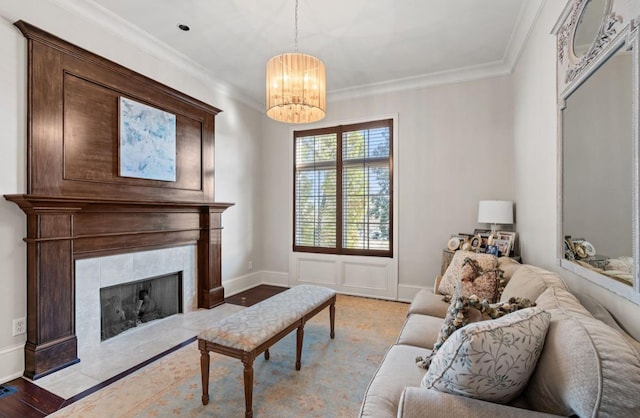 living area featuring ornamental molding, a notable chandelier, a fireplace, and baseboards