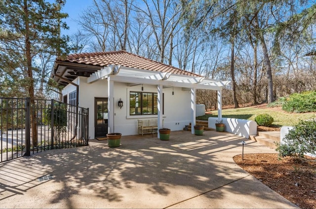 view of front of home featuring a tiled roof, stucco siding, fence, and a pergola