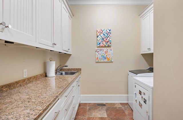 laundry area with washing machine and dryer, cabinet space, a sink, and baseboards