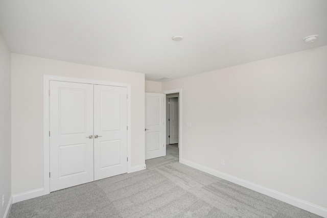 unfurnished bedroom featuring carpet floors, a closet, and baseboards