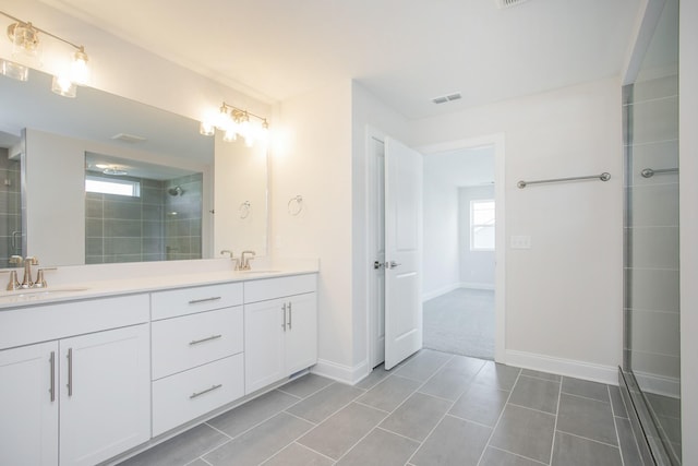 bathroom with double vanity, a tile shower, and a sink