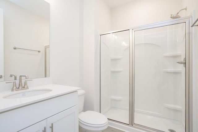 bathroom with vanity, a shower stall, and toilet