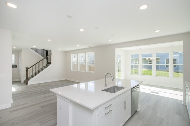 kitchen featuring recessed lighting, stainless steel dishwasher, light wood-style floors, a sink, and baseboards