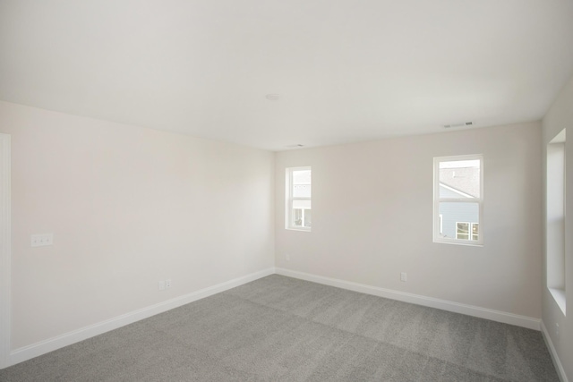 empty room featuring carpet floors, visible vents, and baseboards