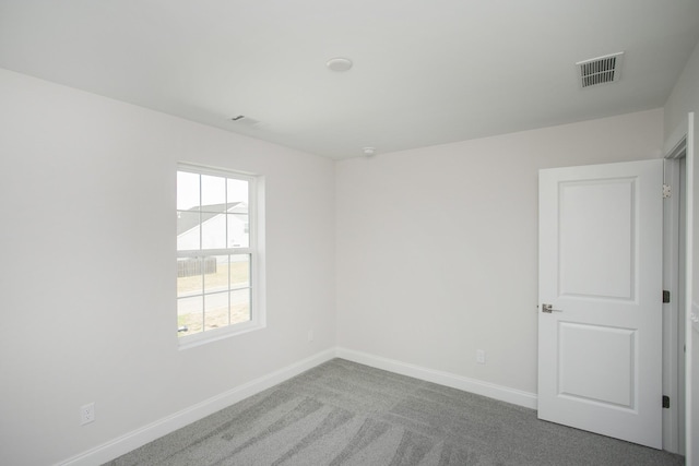 carpeted spare room featuring visible vents and baseboards