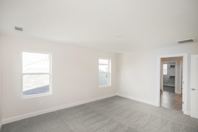 carpeted spare room featuring visible vents and baseboards