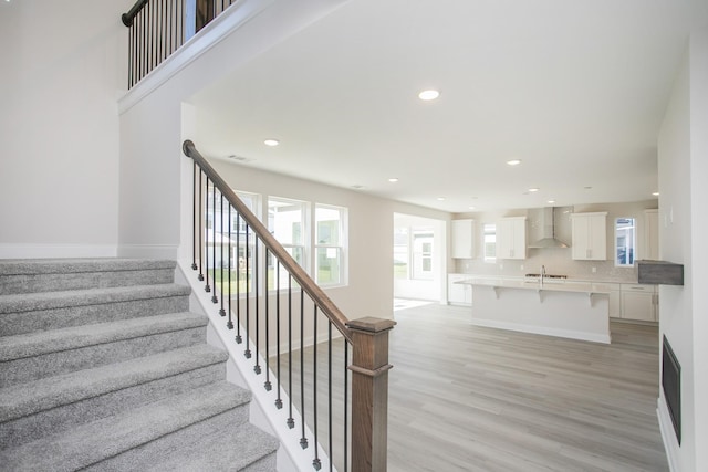 stairs with a wealth of natural light, baseboards, recessed lighting, and wood finished floors