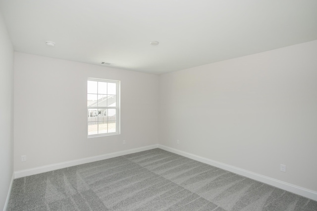 unfurnished room featuring carpet floors, visible vents, and baseboards