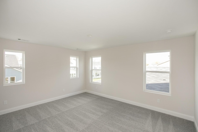 spare room featuring visible vents, baseboards, and carpet flooring