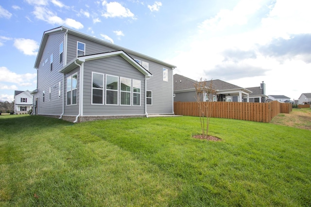 rear view of property with fence and a lawn