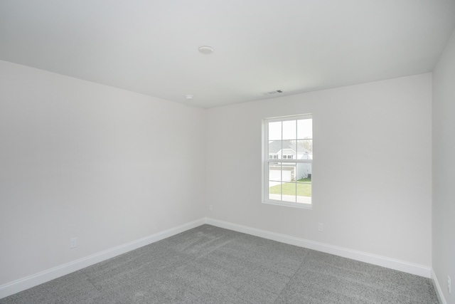 carpeted spare room with visible vents and baseboards