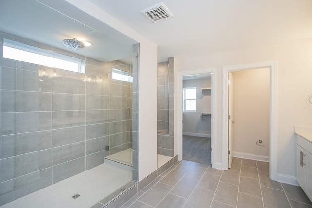 bathroom featuring tiled shower, tile patterned flooring, visible vents, and a healthy amount of sunlight