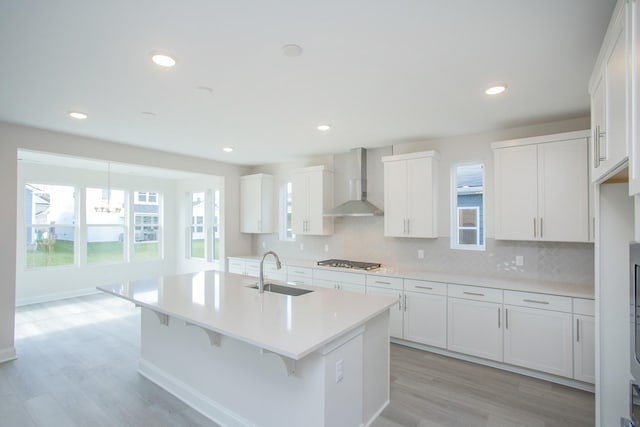 kitchen featuring decorative backsplash, wall chimney exhaust hood, a sink, stainless steel gas stovetop, and a wealth of natural light