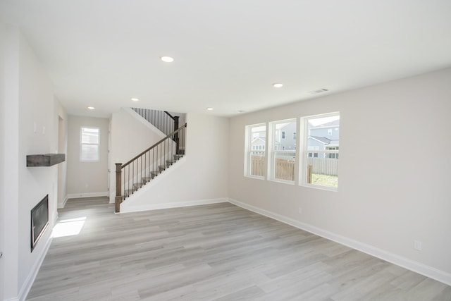 unfurnished living room with recessed lighting, stairway, baseboards, and light wood finished floors