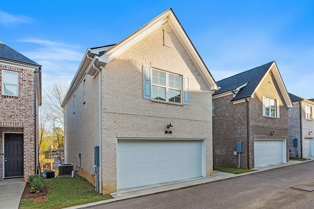 view of side of home featuring a garage, central air condition unit, and brick siding