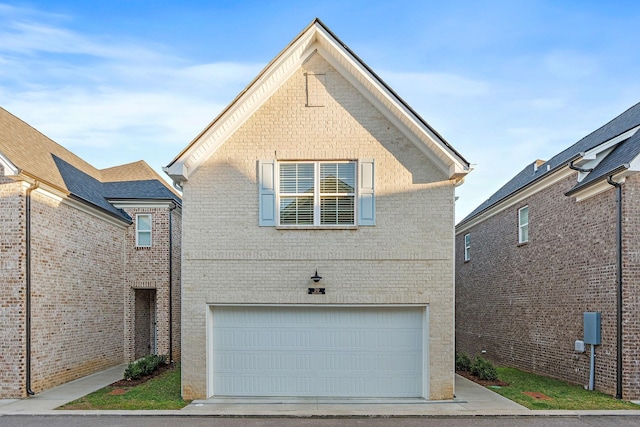 traditional-style house featuring an attached garage, concrete driveway, and brick siding