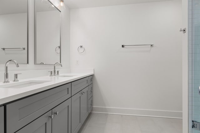 full bathroom featuring double vanity, tile patterned floors, a sink, and baseboards