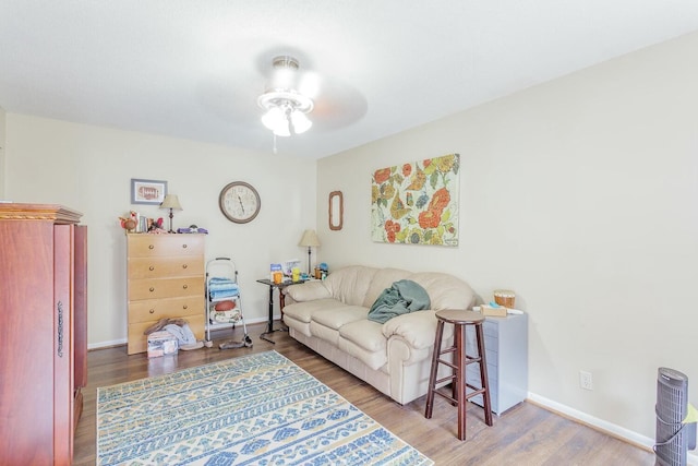 living area featuring ceiling fan, baseboards, and wood finished floors