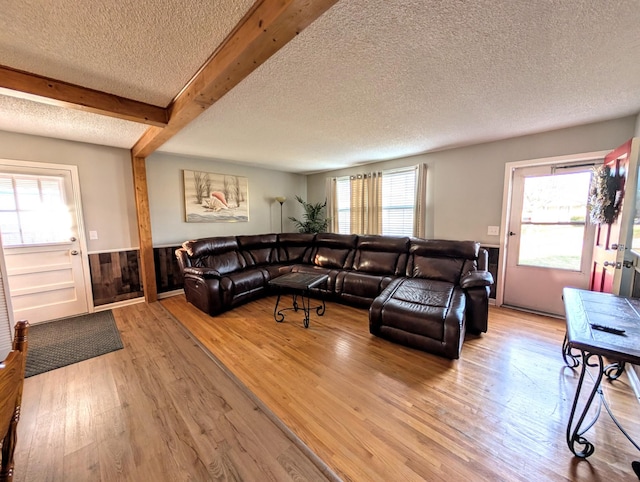 living area featuring plenty of natural light, wainscoting, beamed ceiling, and hardwood / wood-style flooring