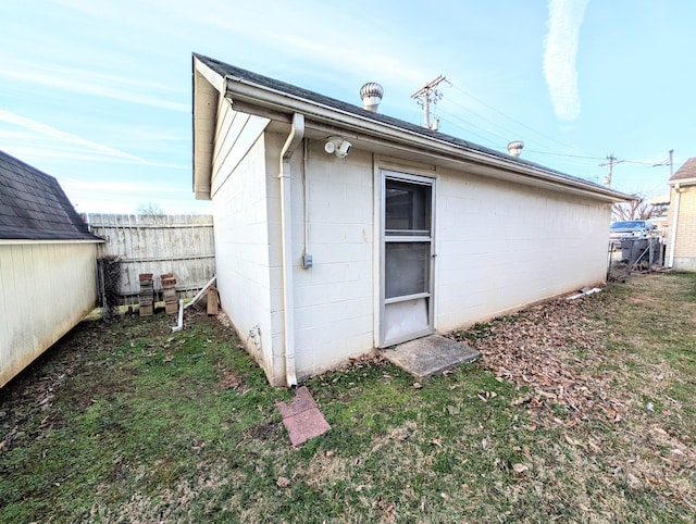 exterior space featuring a yard, concrete block siding, and fence