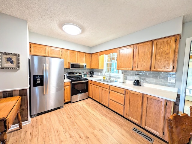 kitchen with light countertops, visible vents, appliances with stainless steel finishes, light wood-style floors, and a sink