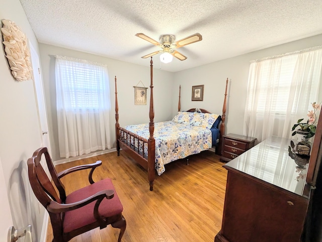 bedroom with light wood-style floors, a textured ceiling, and a ceiling fan