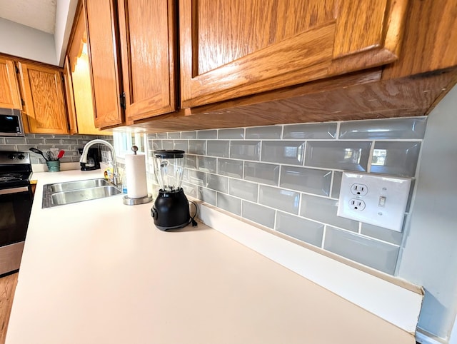 kitchen featuring tasteful backsplash, appliances with stainless steel finishes, light countertops, and a sink