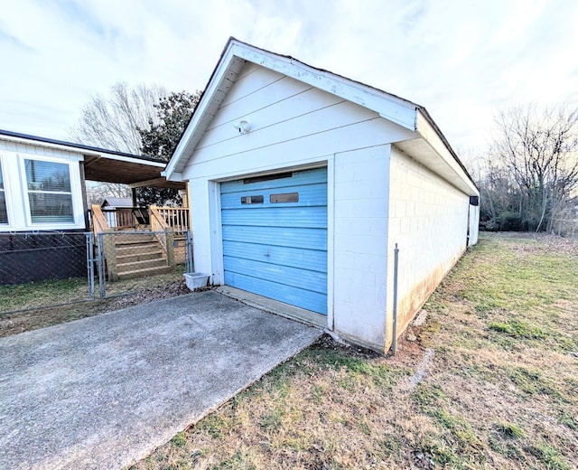 garage featuring a garage, driveway, and fence