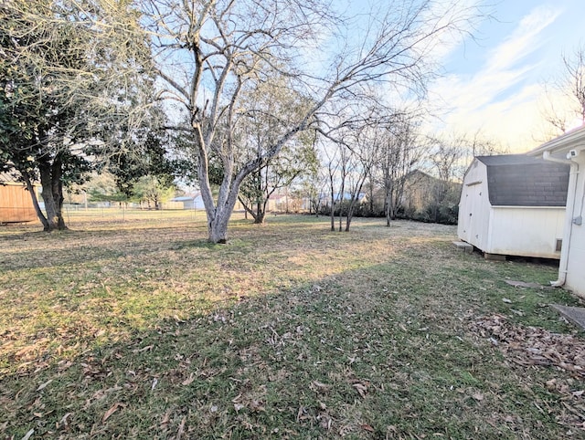 view of yard featuring an outdoor structure, fence, and a shed