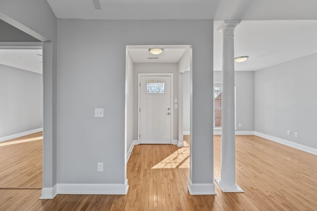 entrance foyer featuring decorative columns, baseboards, visible vents, and wood finished floors