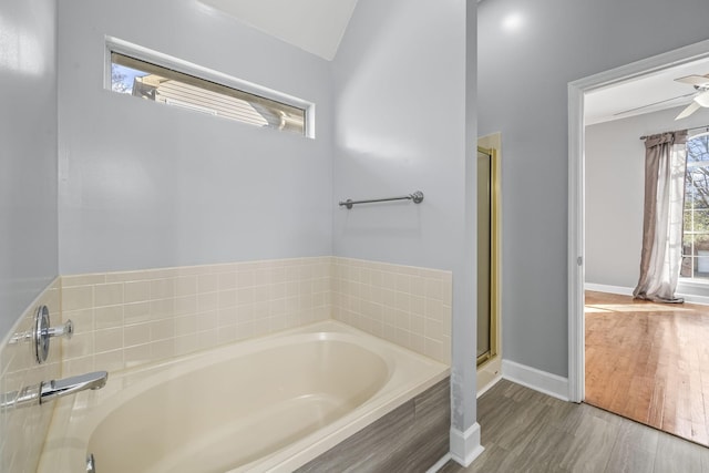 full bathroom featuring wood finished floors, baseboards, a stall shower, ceiling fan, and a bath