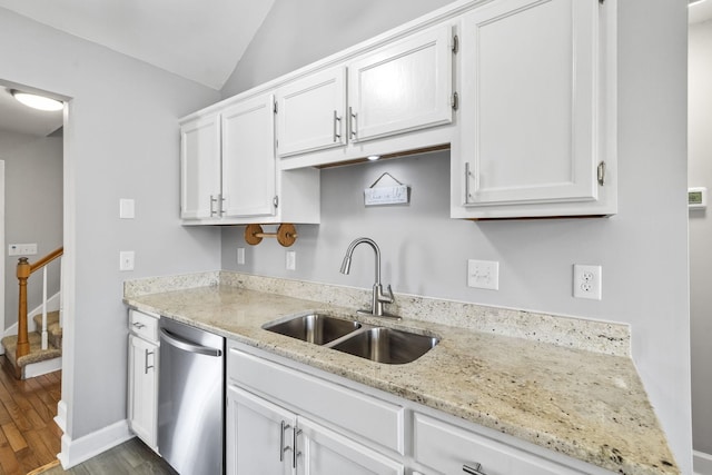 kitchen with stainless steel dishwasher, vaulted ceiling, white cabinets, and a sink