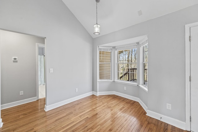 unfurnished dining area featuring light wood-style flooring, high vaulted ceiling, and baseboards