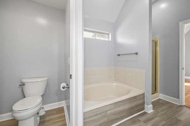 bathroom with toilet, a garden tub, vaulted ceiling, a stall shower, and wood finished floors