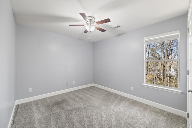 carpeted empty room featuring visible vents, a ceiling fan, and baseboards